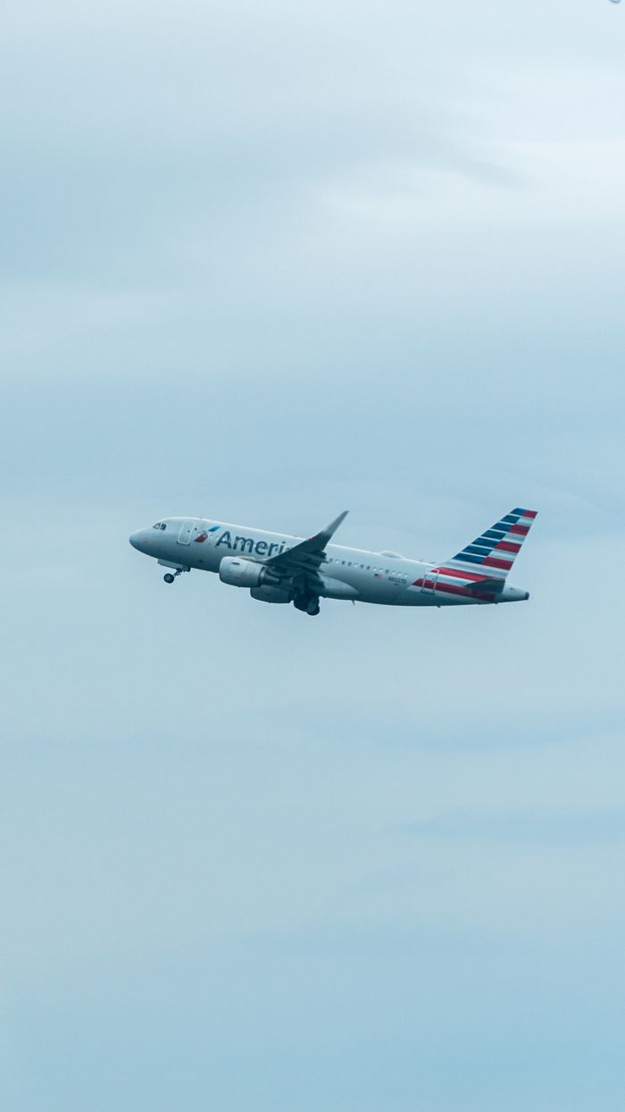 A commercial airplane in flight against an overcast sky, showcasing aviation travel.
